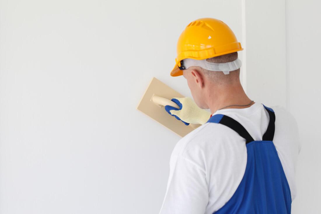 worker finishing the drywall wearing safety hat